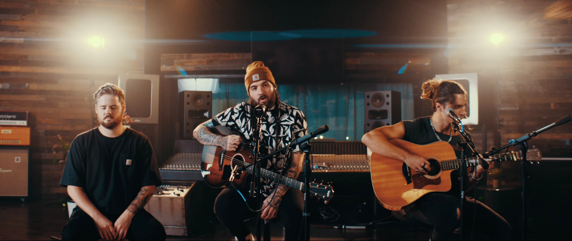 A group of men are playing guitars and singing into microphones in a room.