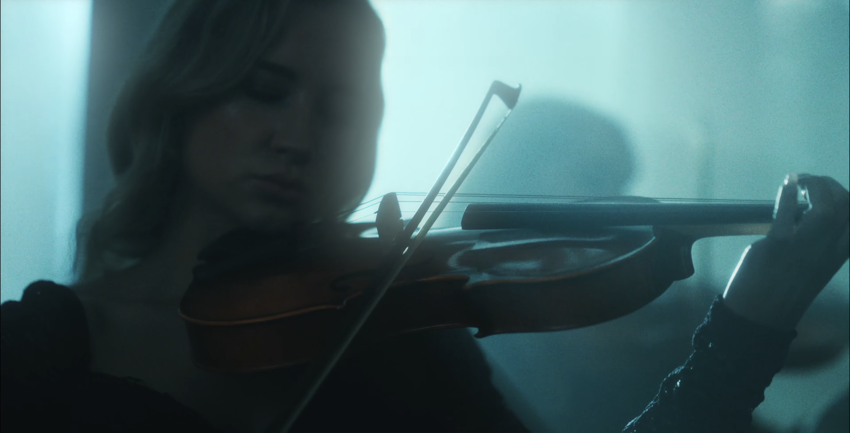 A woman is playing a violin in a dark room. From Letdown - Crying In The Shower (Reimagined)