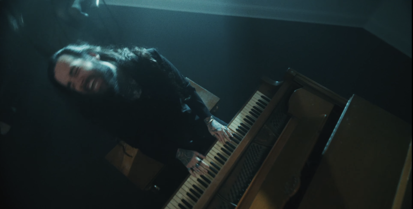 A man is playing a piano in a dark room. From Letdown - Crying In The Shower (Reimagined)