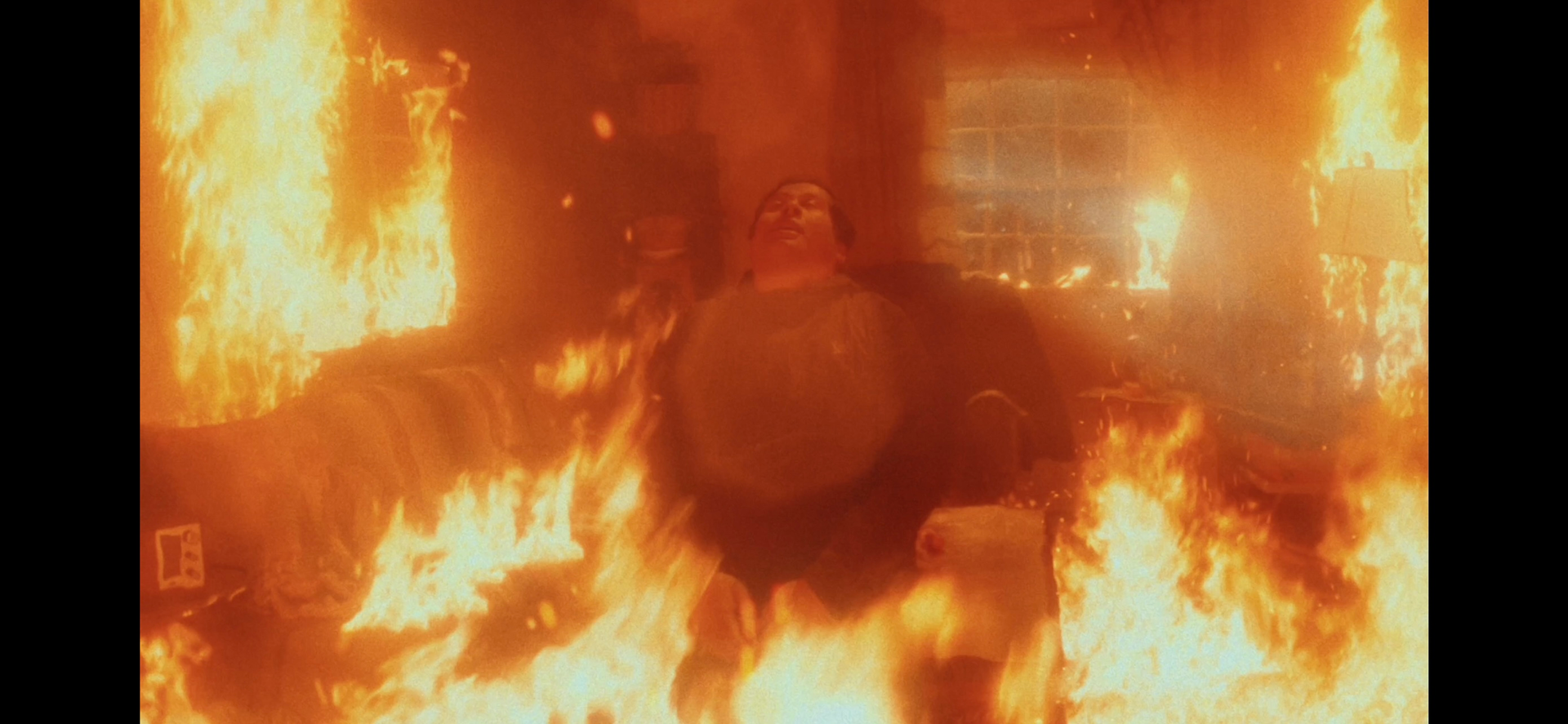 A man is standing in a room filled with flames.