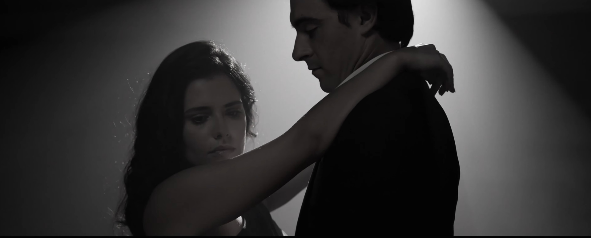 A man and a woman are dancing in a dark room.