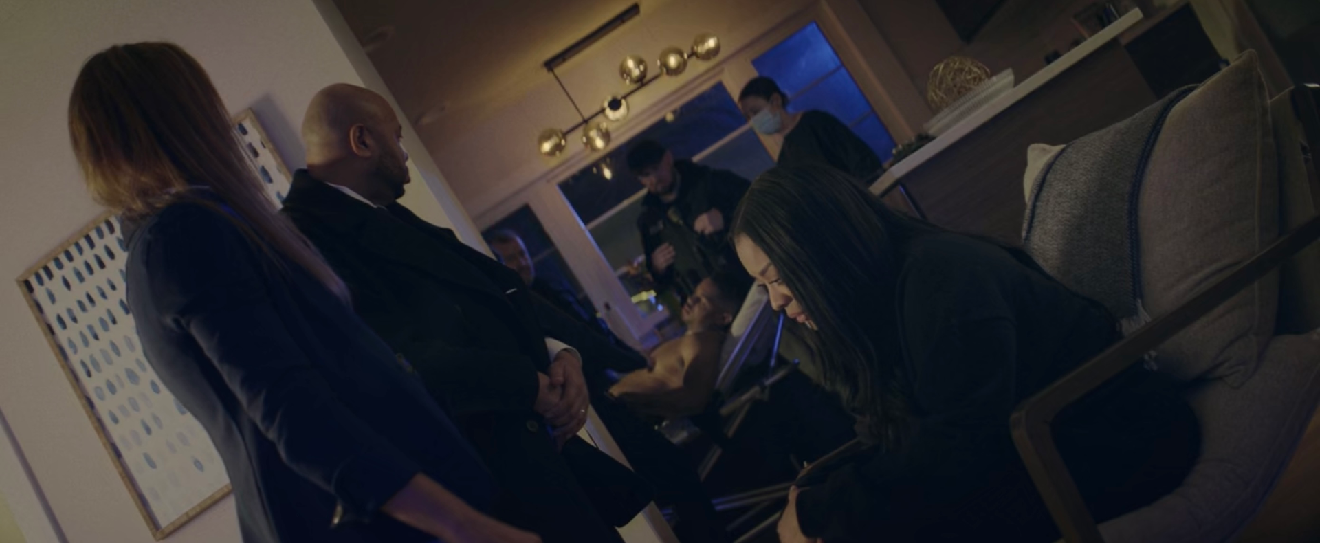 A group of people are standing around a table in a living room. From Dark Deceptions