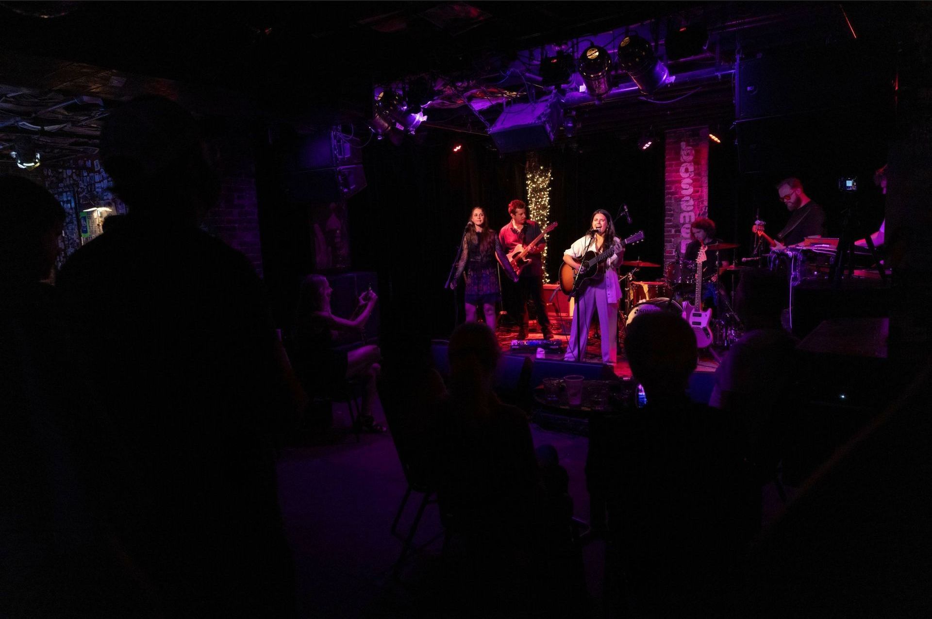 A group of people are playing instruments on a stage in a dark room.