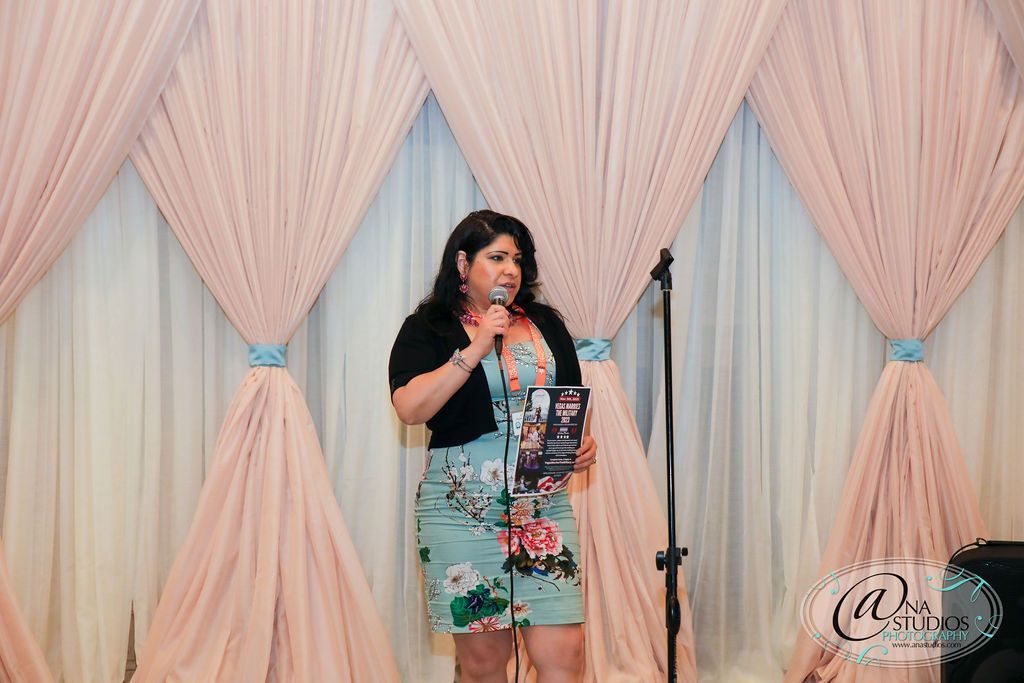 A woman is standing in front of a microphone holding a book.