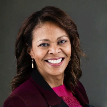 A woman in a black suit is smiling for the camera