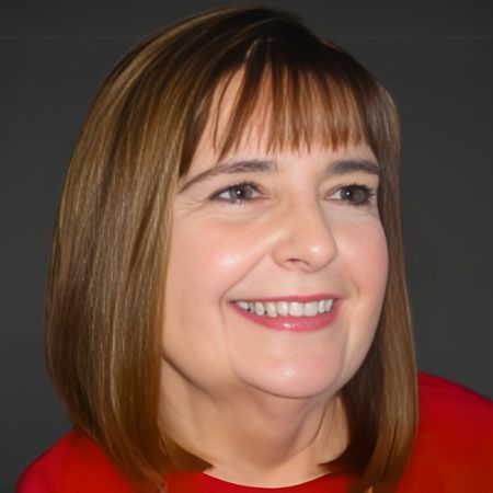 Woman with short, light brown hair and bangs smiles, wearing a red top.