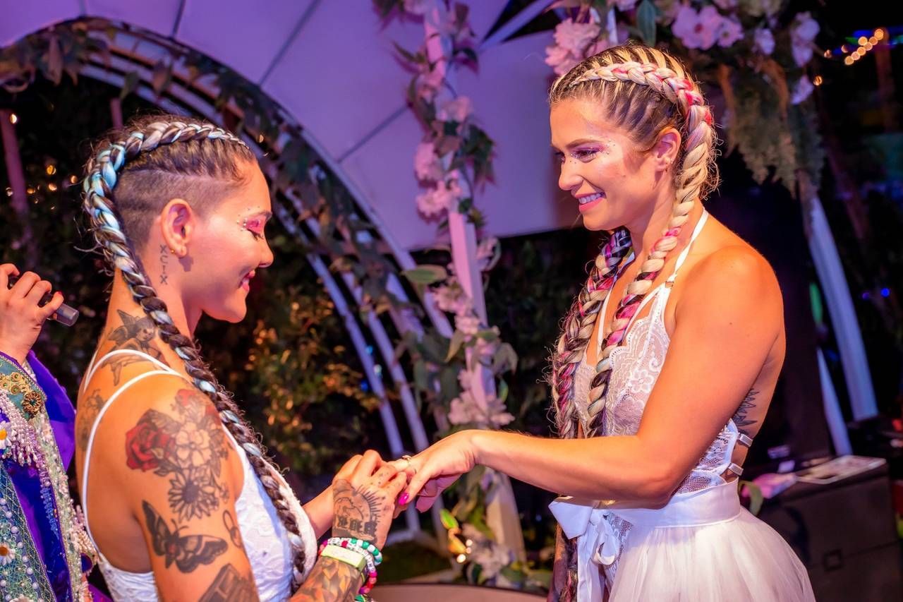 A bride is putting a wedding ring on another bride 's finger.