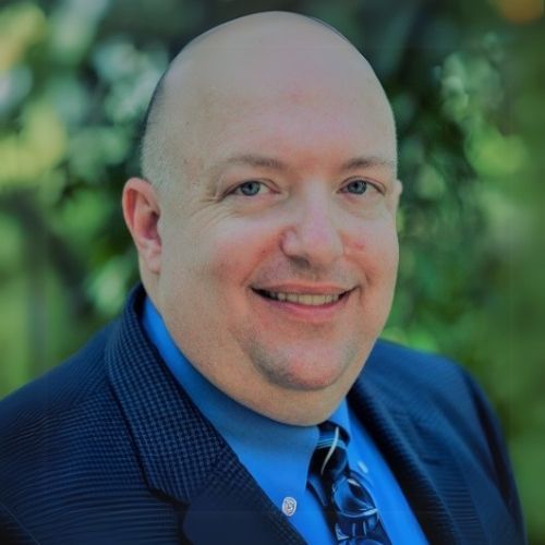 A man in a blue suit smiling at the camera