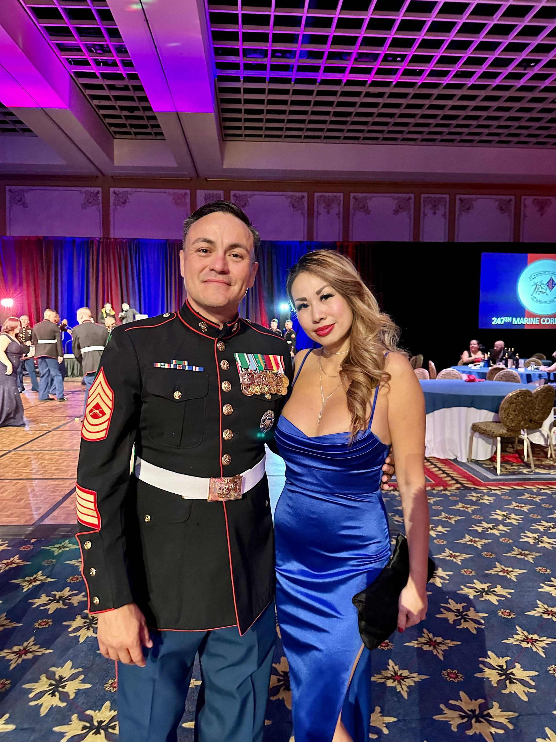 A man in a military uniform and a woman in a blue dress are posing for a picture.
