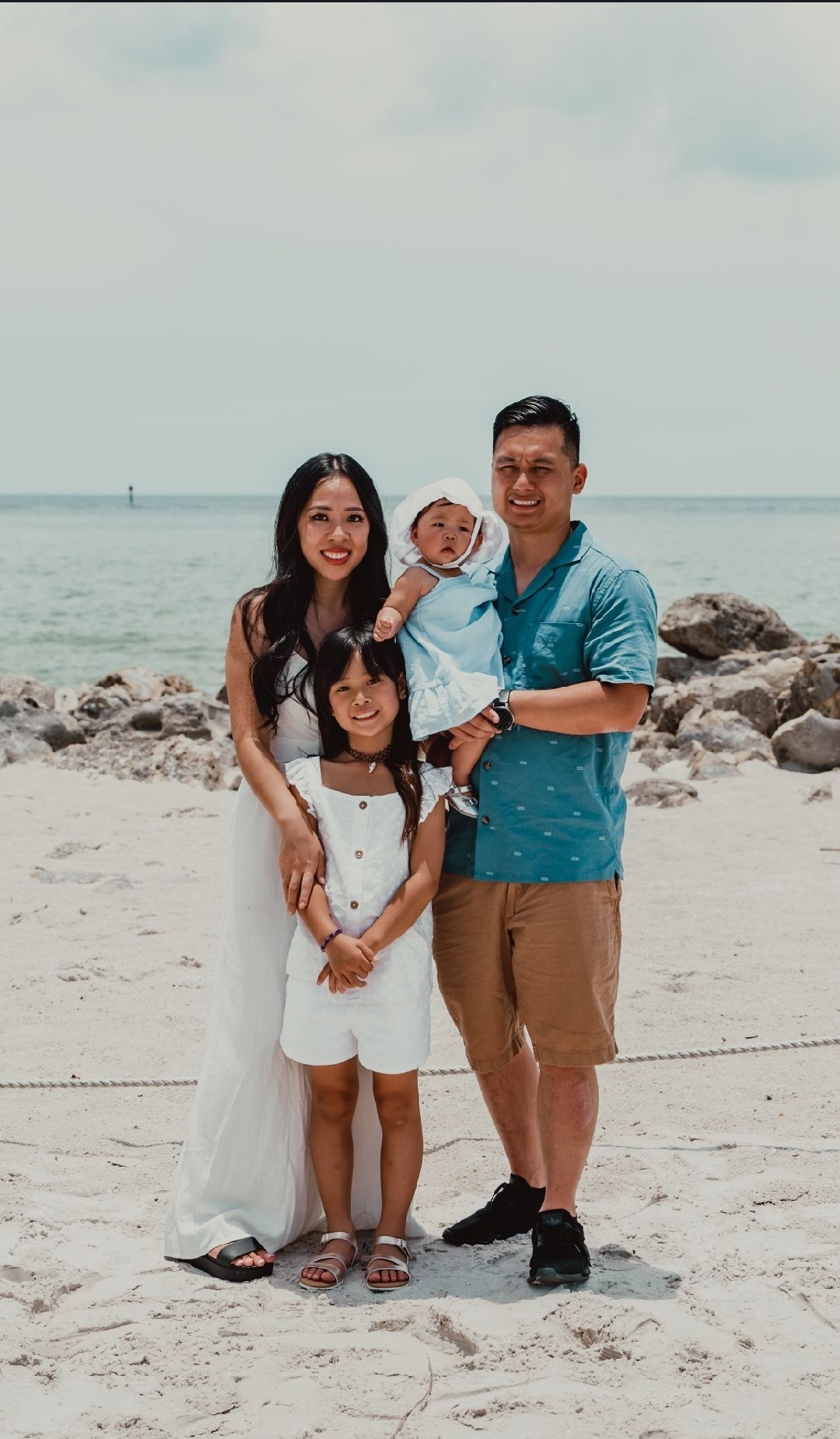 A family is posing for a picture on the beach.