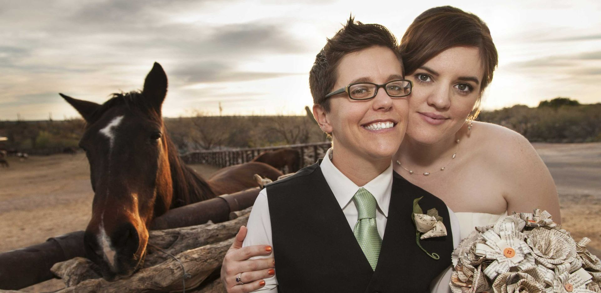 Two women are posing for a picture in front of a horse.