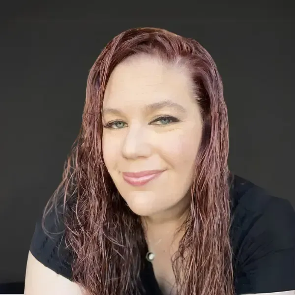 A woman with gray hair and a necklace is smiling for the camera.