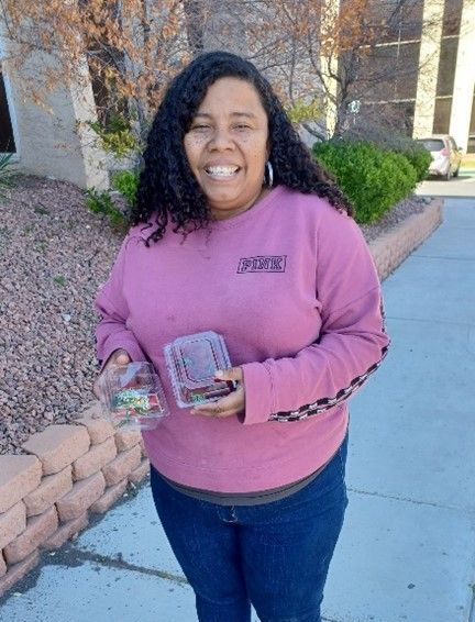 A woman in a pink sweater is holding two boxes of candy.
