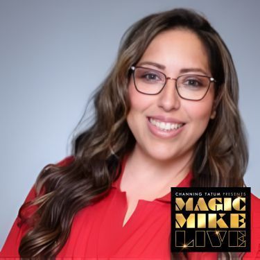 A smiling Stephanie Flores with wavy brown hair and glasses wears a red shirt. The Magic Mike Live logo is in the bottom corner.