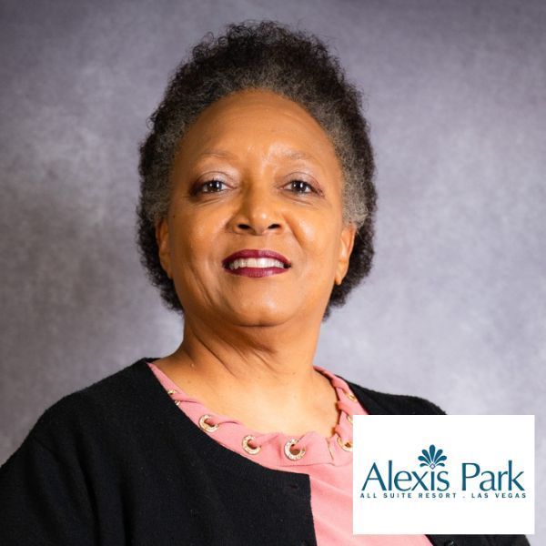 Woman smiling, wearing pink blouse and black jacket, Alexis Park Resort logo.