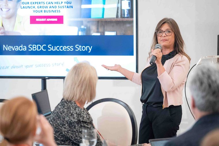 A woman is giving a presentation in front of a group of people.