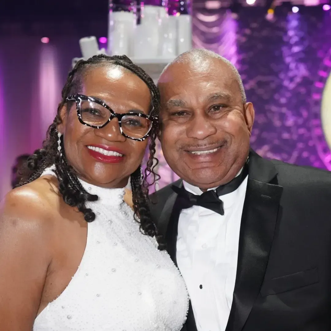 A man in a tuxedo and a woman in a white dress are posing for a picture.