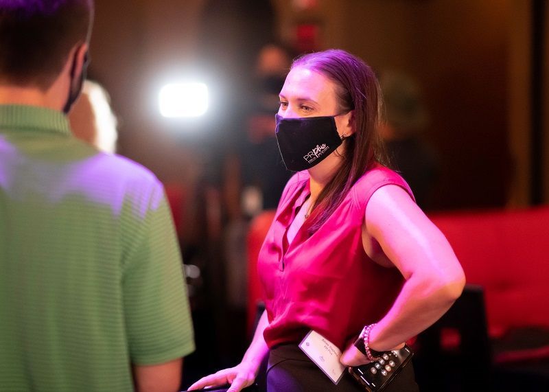 A woman wearing a mask is standing next to a man wearing a green shirt.