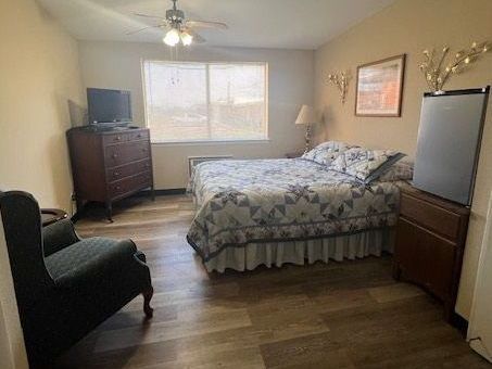A bedroom with a bed , chair , dresser and television.