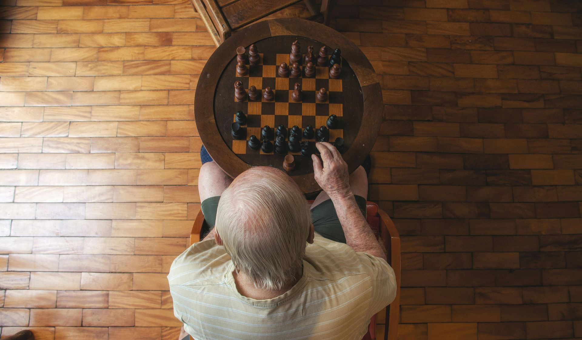 A man is sitting at a table playing a game of chess.