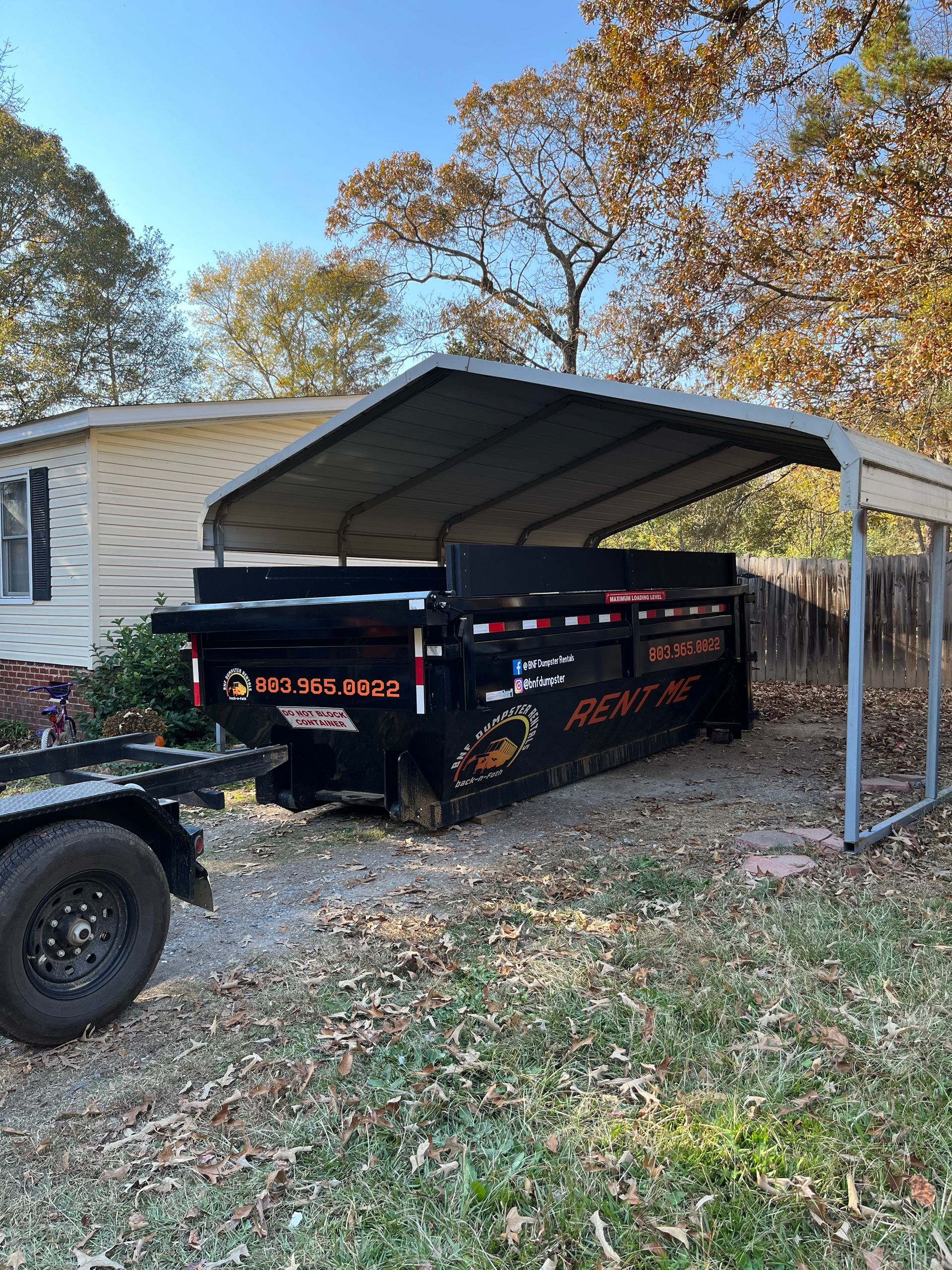 a dumpster is parked under a canopy in front of a house .