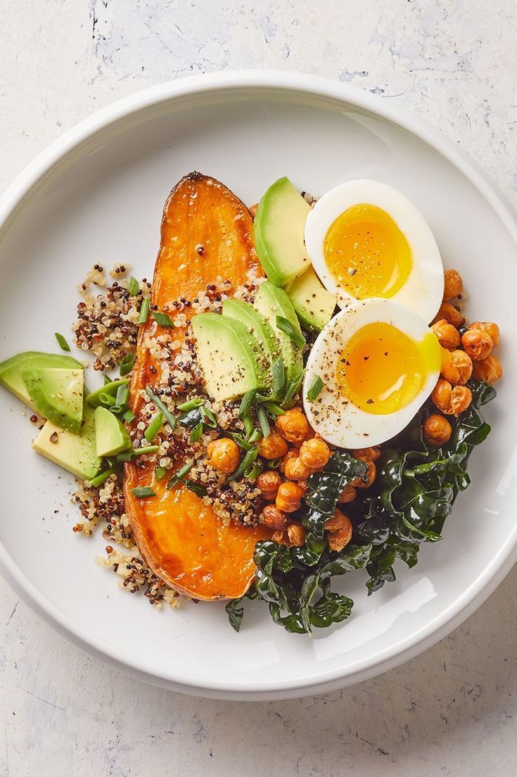 A white plate topped with eggs , avocado , chickpeas , and sweet potatoes.