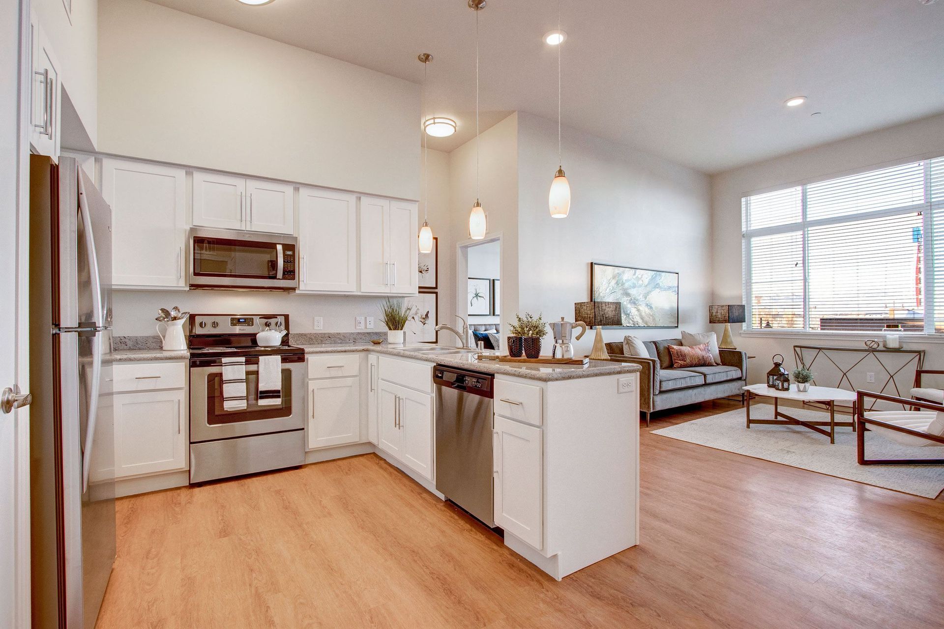 A kitchen with white cabinets , stainless steel appliances , a refrigerator and a microwave.