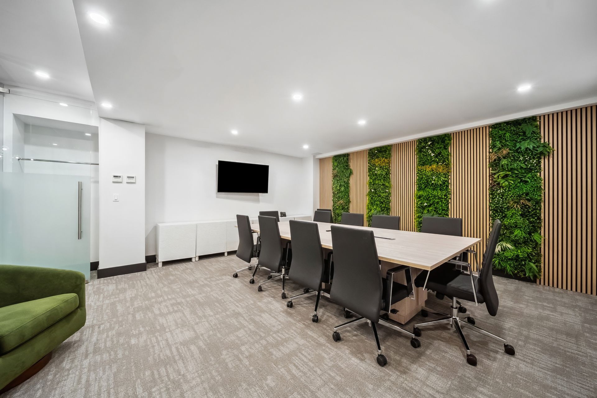 A conference room with a long table and chairs and a green chair.