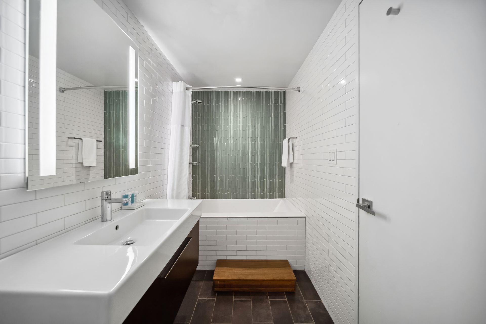 A bathroom with two sinks , a tub and a mirror.