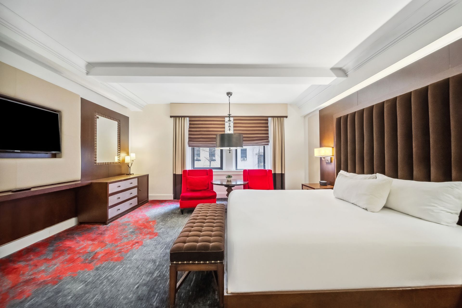 A hotel room with a king size bed , chairs and a flat screen tv.