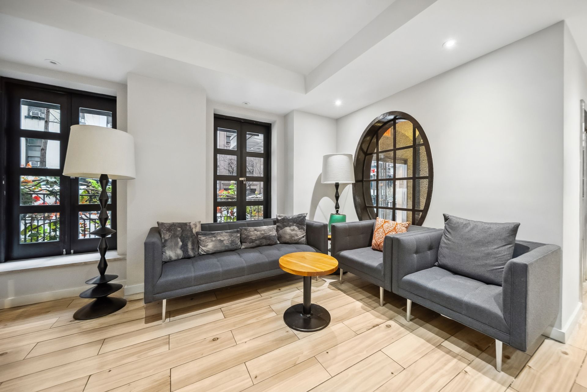 A living room with a couch , chairs , a table and a lamp.