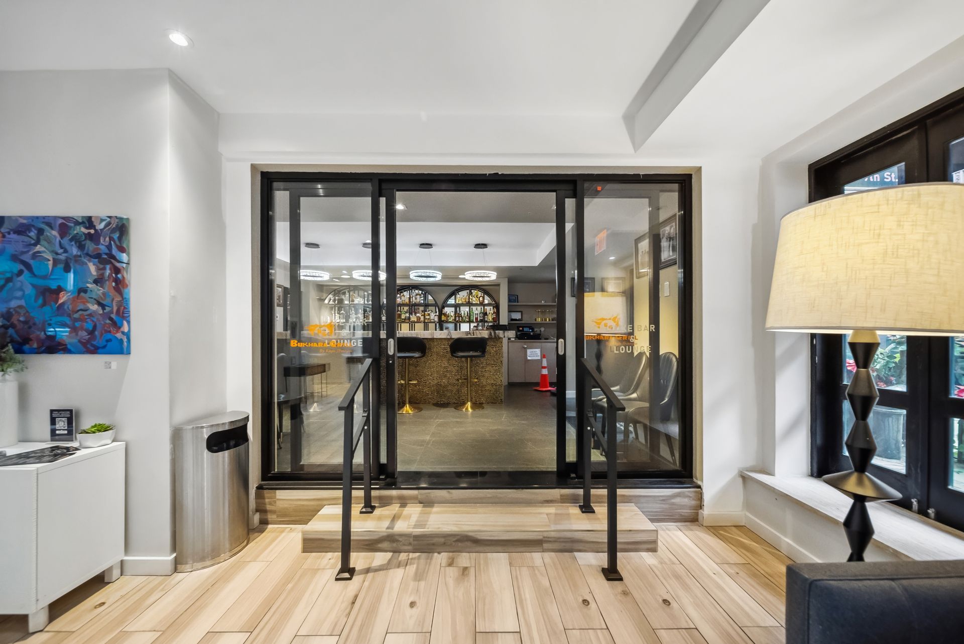 A living room with hardwood floors and sliding glass doors leading to a restaurant.