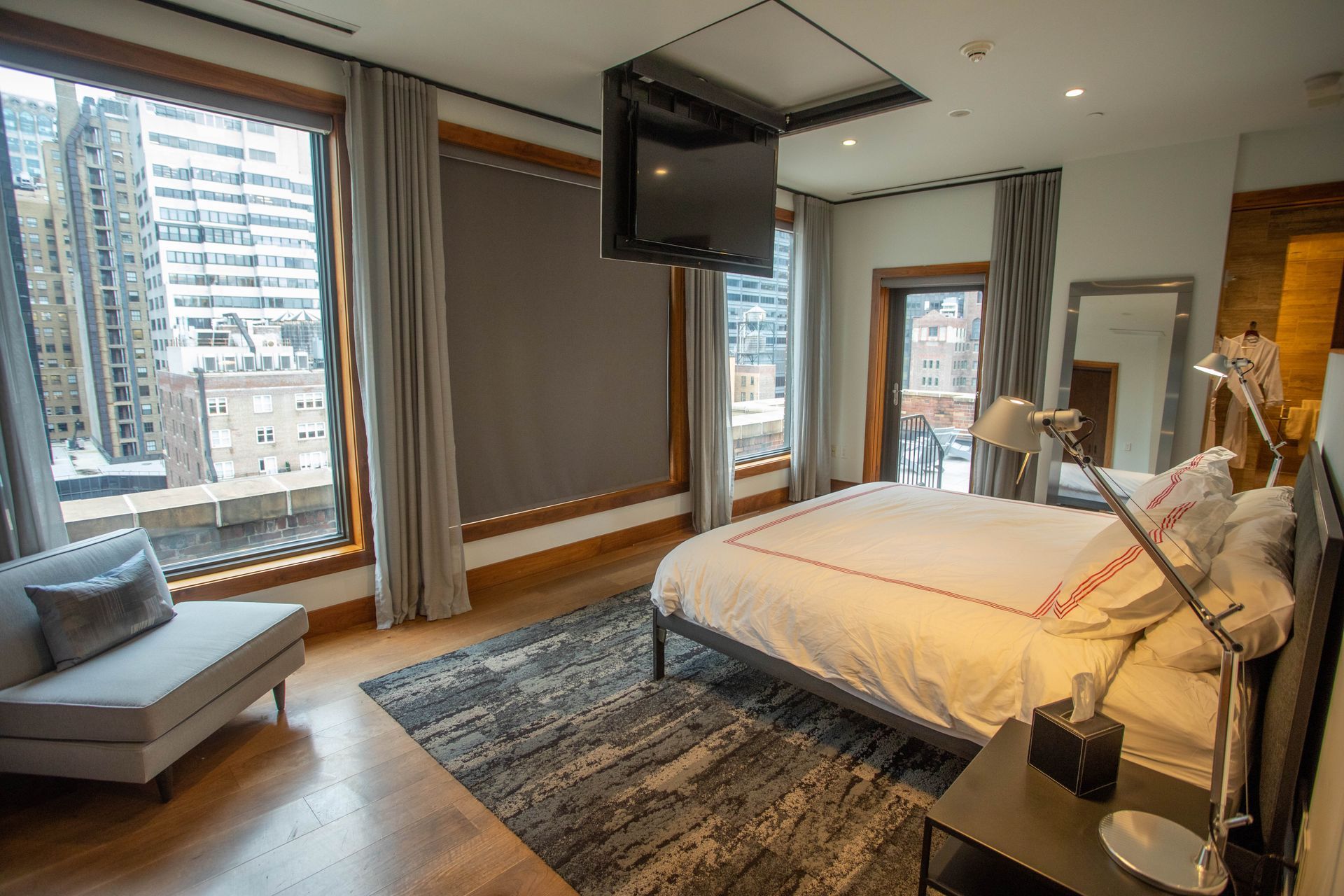 A hotel room with a large bed and a flat screen tv hanging from the ceiling.