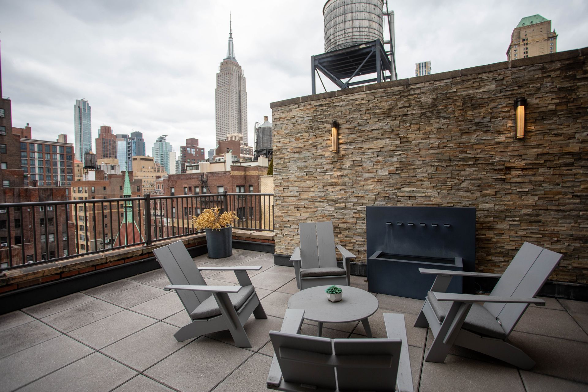 A rooftop patio with chairs , tables and a water tower.