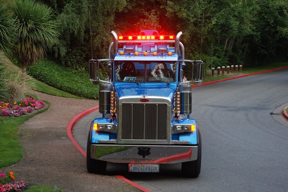 A blue peterbilt semi truck is driving down a road