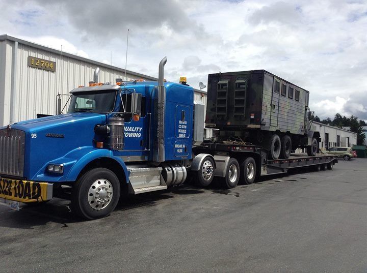 A blue semi truck is parked in front of a building