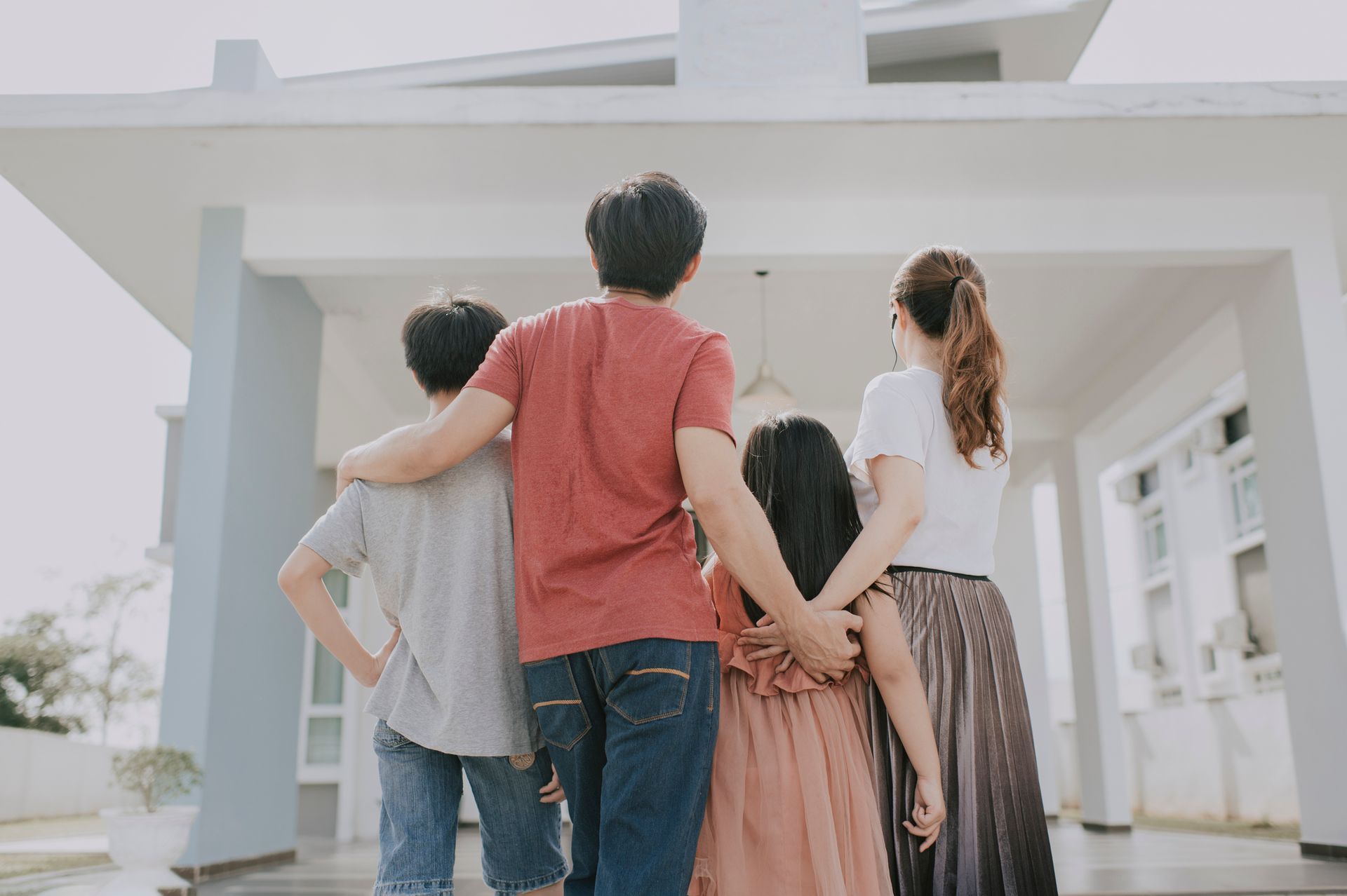 A family is standing in front of a house looking at it.