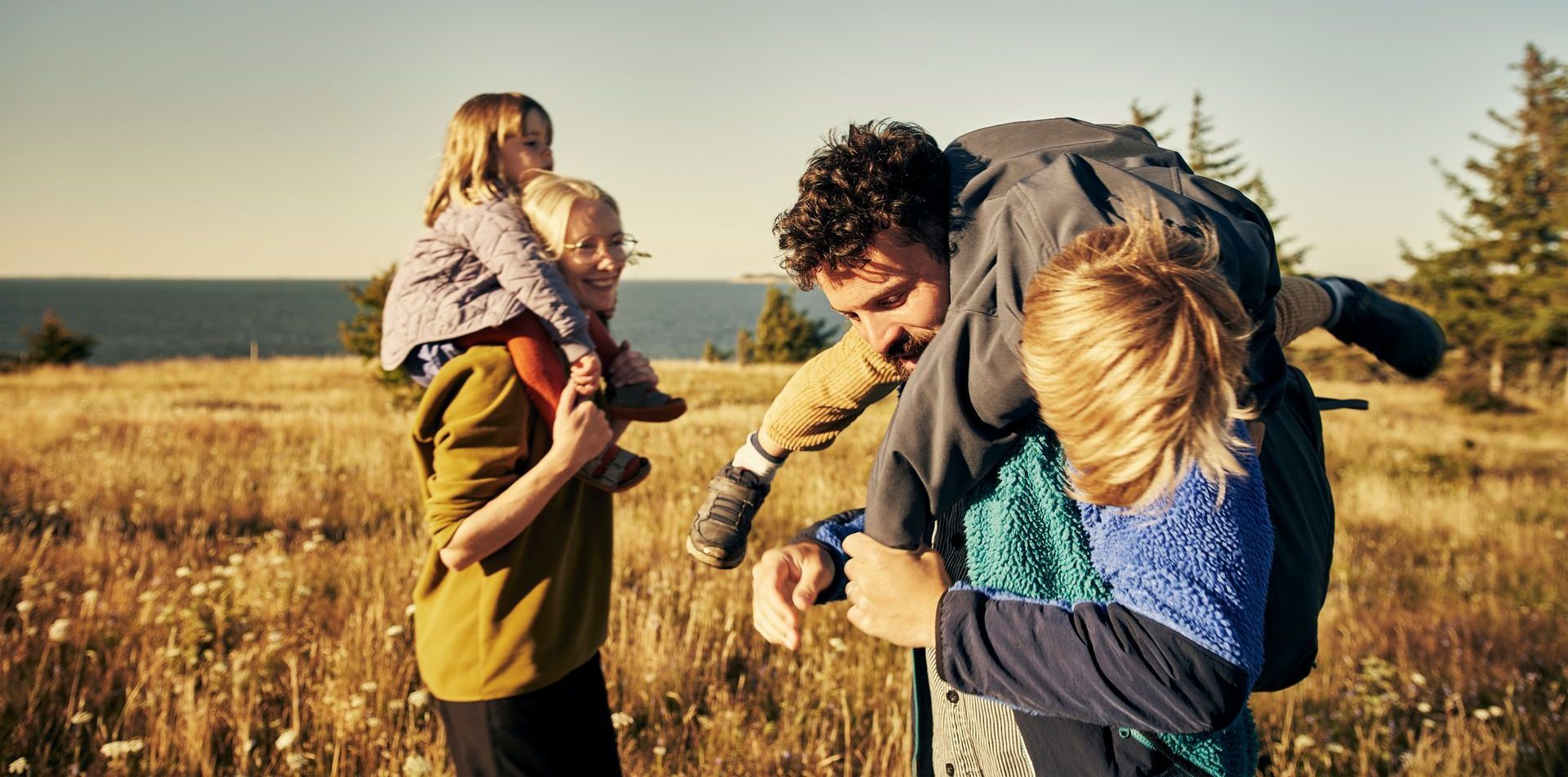 A man is carrying a child on his shoulders in a field.