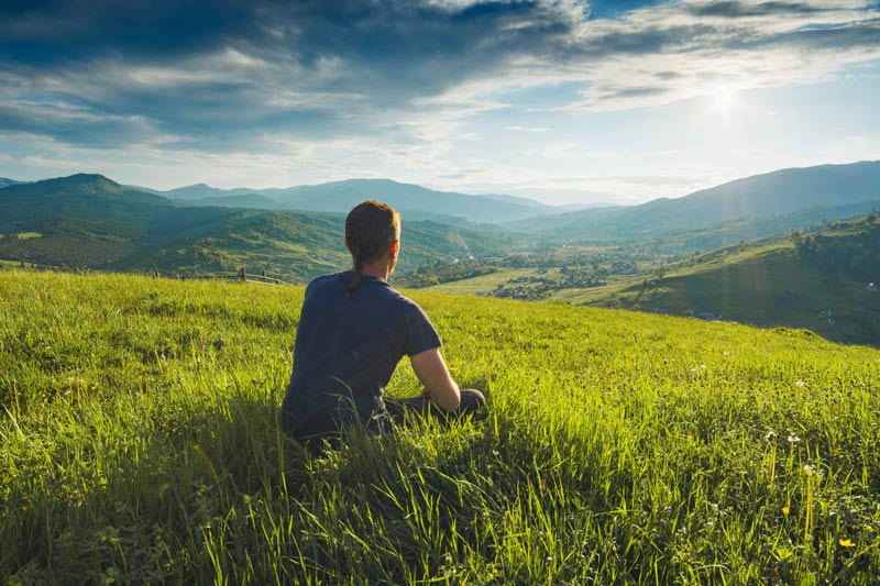 young man sitting in field of grass