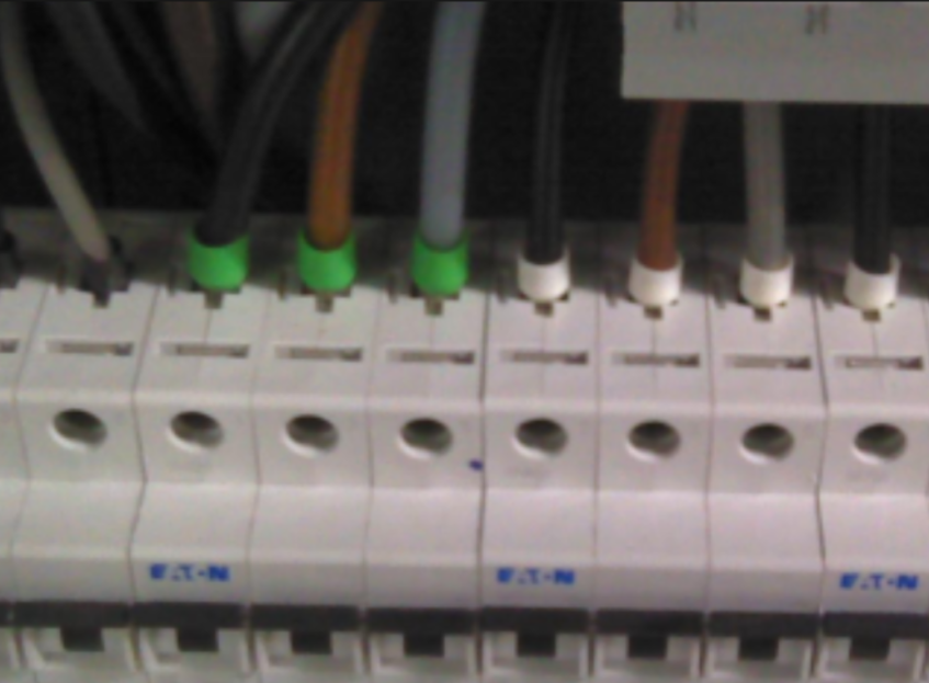 En rad med Eaton-sikringer koblet med kabler merket med grønne og hvite fargekodede ringer.