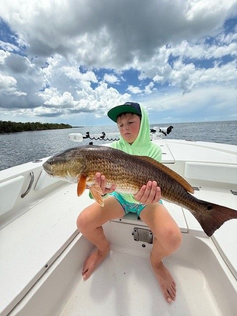 A woman is holding a large fish on a boat.
