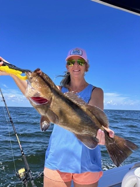 A man is holding a large fish on a boat in the ocean.