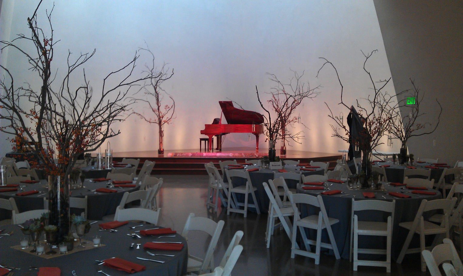 Wedding reception setup with a piano on the stage and grapevine wigs decorating the area