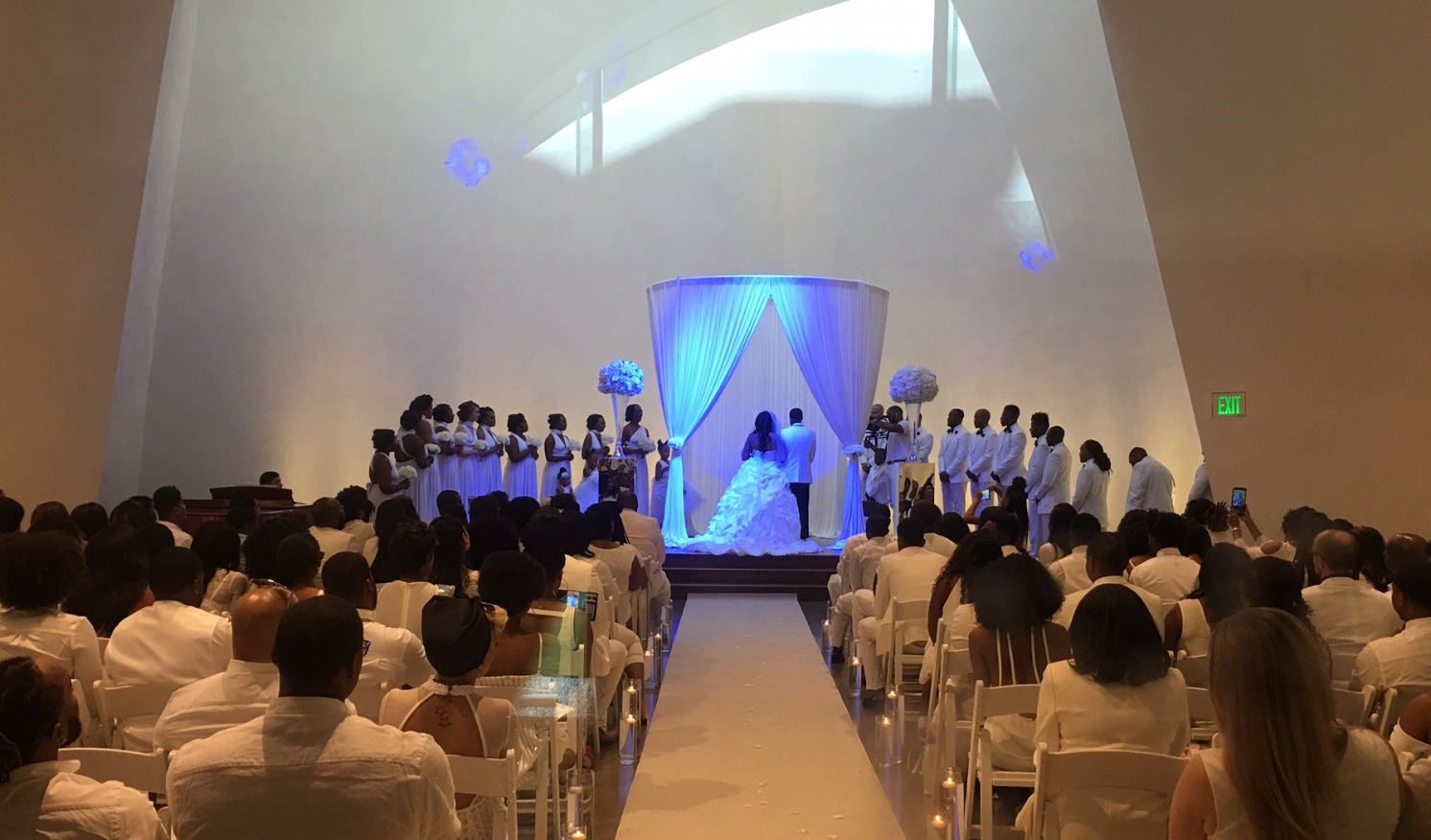 Wedding in progress with a white interior decorating and a canopy over the Bride and Groom.