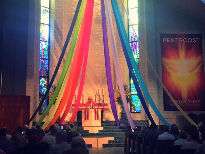 Sanctuary decorated with LGBTQ Pride colored banners hanging down around the alter