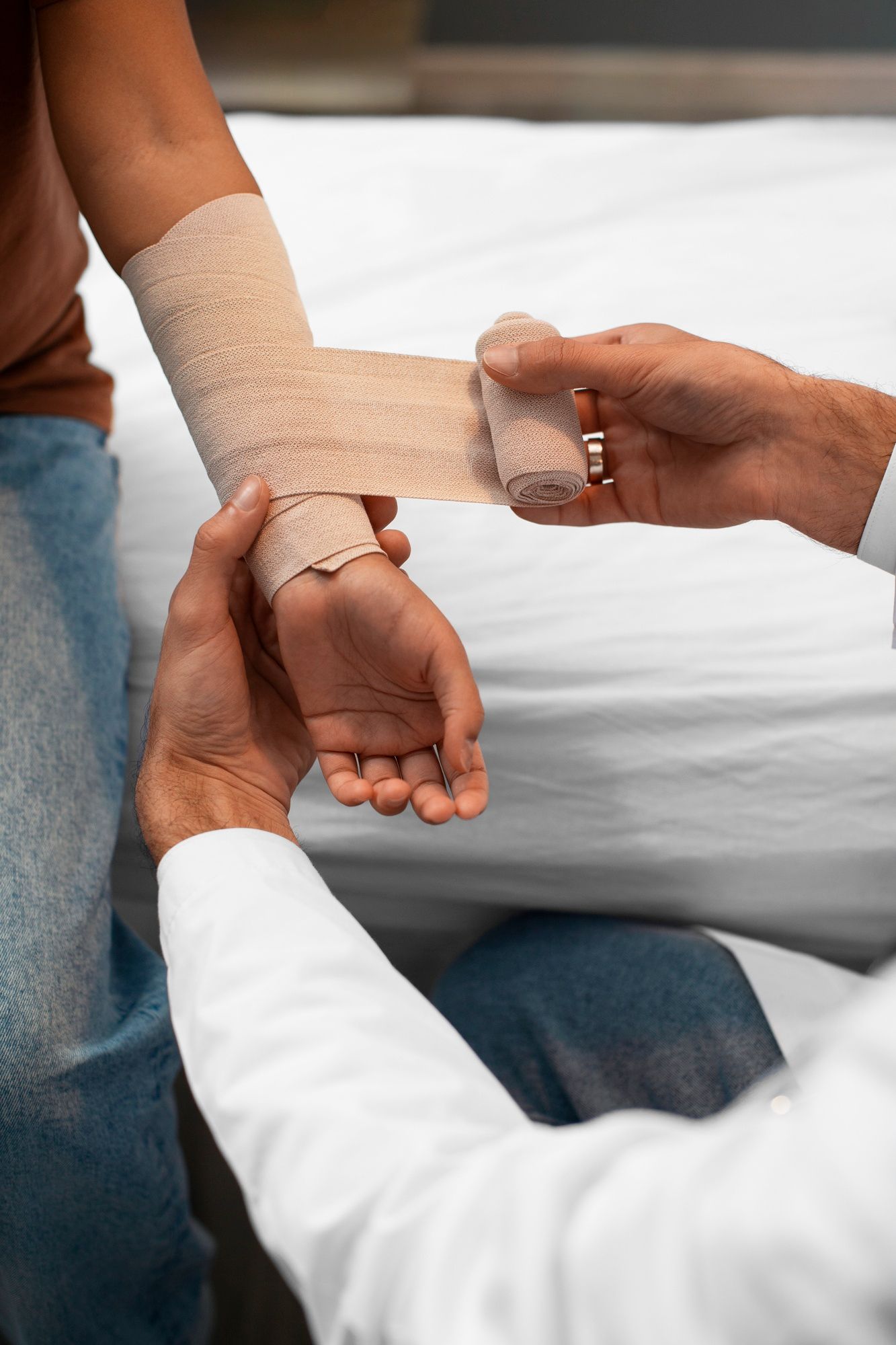 A doctor is wrapping a patient 's wrist with a bandage.