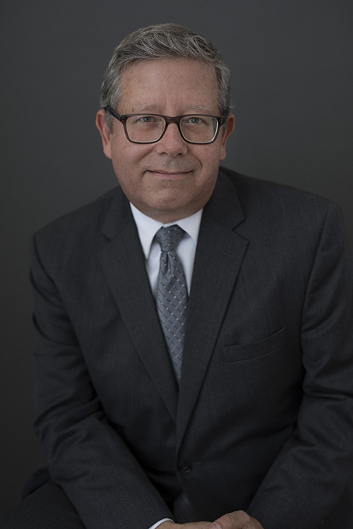 A man in a suit and tie is sitting down and smiling.