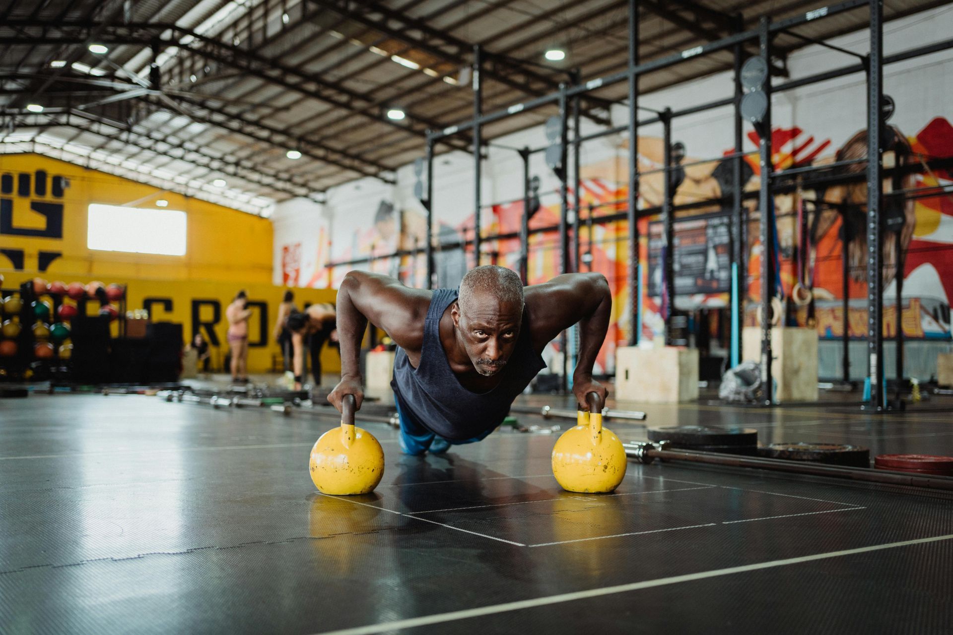 A man is doing push ups with kettlebells in a gym.