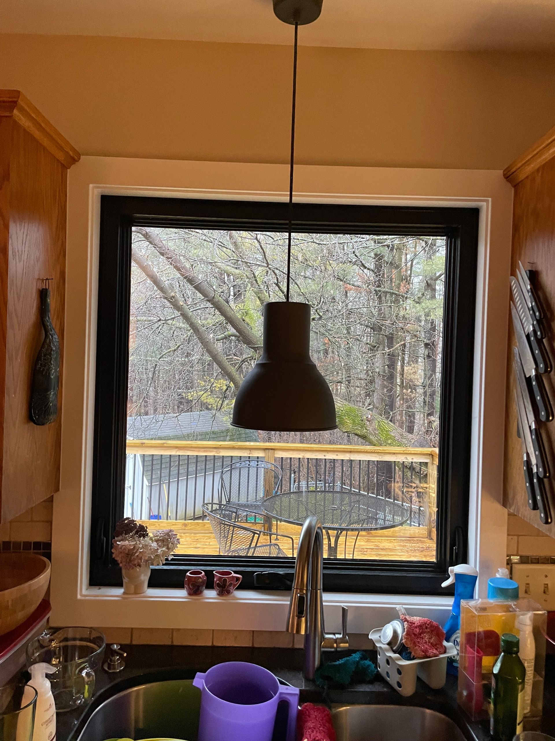 A kitchen with a sink and a window with a light hanging from the ceiling.