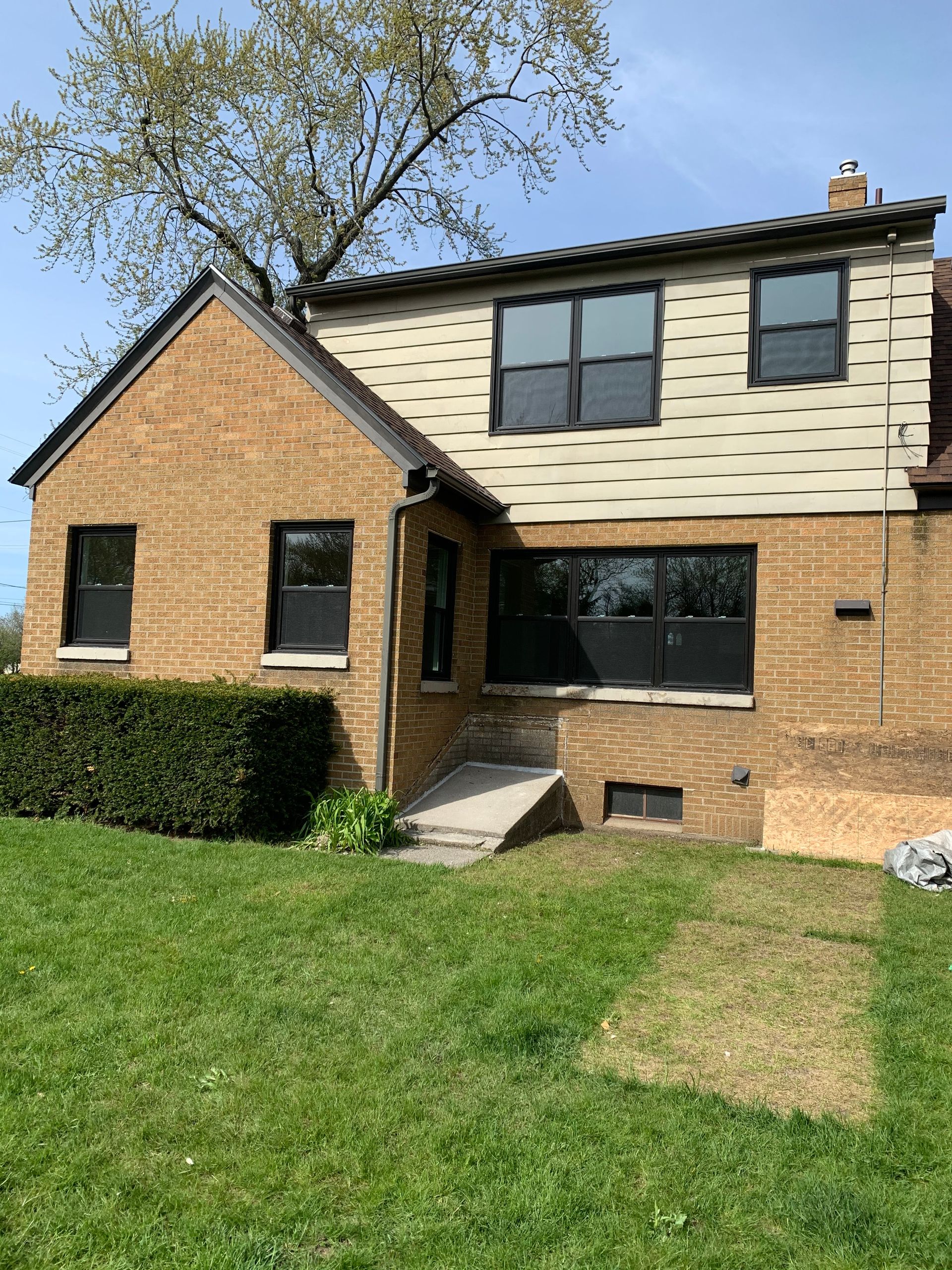 A brick house with a large lawn in front of it.